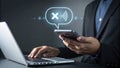 Businessman canceling a notification message on smartphone while working on laptop, managing tasks and communications in the Royalty Free Stock Photo