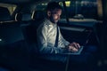 Businessman in car working on laptop in back seat Royalty Free Stock Photo