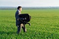 Businessman carries an office chair in a field to work, freelance and business concept, green grass and blue sky as background Royalty Free Stock Photo