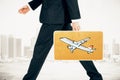 Businessman carries a suitcase with plane print at city background
