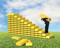 Businessman carrying bullion climbing on gold stairs