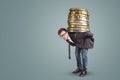 Businessman carrying a giant stack of coins on his back