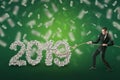 Businessman catches `2019` dollar sign with rope lasso and money in the air on green background Royalty Free Stock Photo