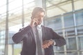 Businessman checking time while talking on mobile phone in lobby office Royalty Free Stock Photo