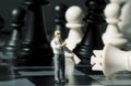 Businessman and chess figures on game board. Playing chess with miniature doll macro photo. Royalty Free Stock Photo