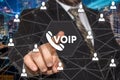 The businessman chooses VOIP button on the touch screen with a futuristic background .The concept VOIP. Royalty Free Stock Photo