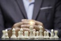 Businessman clasped hands behind crowd chess figures for thinking planing strategy. Business plan and strategic business tactic