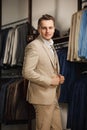 Businessman in classic vest against row of suits in shop. A young stylish man in a black cloth jacket. It is in the showroom, tryi