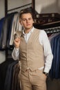 Businessman in classic vest against row of suits in shop. A young stylish man in a black cloth jacket. It is in the showroom, tryi