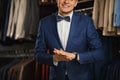 Businessman in classic vest against row of suits in shop. A young stylish man in a black cloth jacket. It is in the showroom, tryi