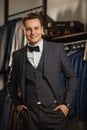 Businessman in classic vest against row of suits in shop. A young stylish man in a black cloth jacket. It is in the showroom, tryi