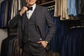 Businessman in classic vest against row of suits in shop. A young stylish man in a black cloth jacket. It is in the showroom, tryi