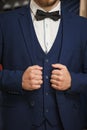 Businessman in classic vest against row of suits in shop. A young stylish man in a black cloth jacket. It is in the showroom, tryi