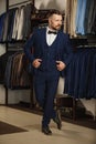 Businessman in classic vest against row of suits in shop. A young stylish man in a black cloth jacket. It is in the showroom, tryi