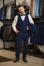 Businessman in classic vest against row of suits in shop. A young stylish man in a black cloth jacket. It is in the showroom, tryi