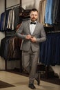 Businessman in classic vest against row of suits in shop. A young stylish man in a black cloth jacket. It is in the showroom, tryi