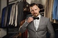 Businessman in classic vest against row of suits in shop. A young stylish man in a black cloth jacket. It is in the showroom, tryi