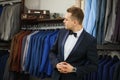 Businessman in classic vest against row of suits in shop. A young stylish man in a black cloth jacket. It is in the showroom, tryi