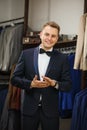 Businessman in classic vest against row of suits in shop. A young stylish man in a black cloth jacket. It is in the showroom, tryi