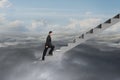 Businessman climbing on concrete stairs with natural cloudy sky