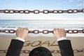 Businessman climbing on iron chains with goal word sand beach