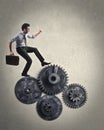 Businessman climbing on mechanism wheels