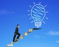 Businessman climbing the money stairs toward light bulb Royalty Free Stock Photo