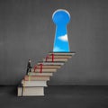 Businessman climbing on stack books to key shape door