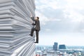 Businessman climbing up a huge stack of paper Royalty Free Stock Photo