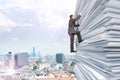 Businessman climbing up a huge stack of paper Royalty Free Stock Photo