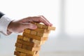 Businessman collapsing stacked tower wood block by hand as failure or bankrupt project. Business organization and company