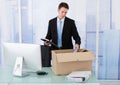 Businessman collecting office supply in cardboard box at desk Royalty Free Stock Photo