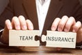 Businessman collects puzzles with the words Team Insurance. Security and safety in a business team. Care for employees. A