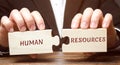 Businessman collects wooden puzzles with the word Human resources. Recruitment, HR, leadership and teambuilding. Business and
