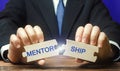 Businessman collects wooden puzzles with the words Mentorship. Business support. The concept of personal and professional