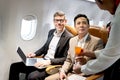 Businessman in comfortable seat inside airplane, female cabin crew air hostess serving orange juice drink, flight attendant take Royalty Free Stock Photo