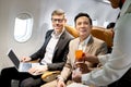 Businessman in comfortable seat inside airplane, female cabin crew air hostess serving orange juice drink, flight attendant take Royalty Free Stock Photo