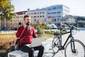 Businessman commuter with electric bicycle sitting on bench, using laptop and smartphone. Royalty Free Stock Photo