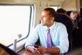 Businessman Commuting To Work On Train Using Mobile Phone