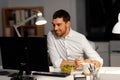 Businessman at computer eating at night office Royalty Free Stock Photo