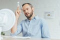 businessman cooling himself with bottle of water and conditioning air with electric fan