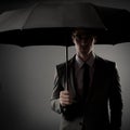 Businessman in costume holding black umbrella