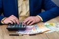 businessman counts euros using a calculator