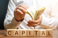 Businessman counts money on the background of the caption Capital. Capitalism, capital increase and influence. Financial