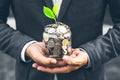 Businessman cover growing plant with coin money