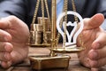 Businessman Covering Light Bulb And Coins On Weighing Scale