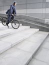 Businessman In Crash Helmet Riding Bicycle Down Steps Royalty Free Stock Photo