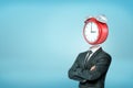 A businessman with crossed arms stands in half-turn with a large red alarm clock instead of his head. Royalty Free Stock Photo