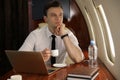 Businessman with cup of coffee looking out window in airplane Royalty Free Stock Photo