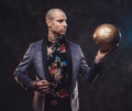 Businessman in custom dark suit poses with golden ball Royalty Free Stock Photo